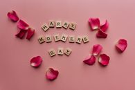 Scrabble tiles spelling 'Happy Mother's Day' surrounded by pink petals.