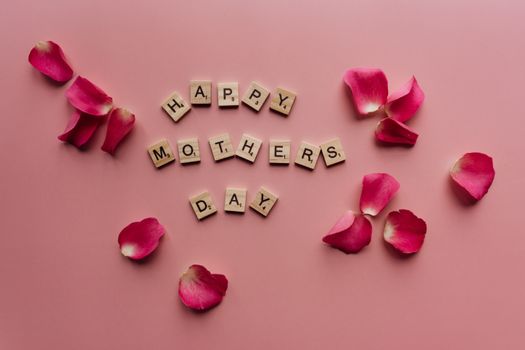 Scrabble tiles spelling 'Happy Mother's Day' surrounded by pink petals.