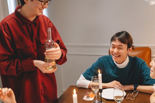 Free Friends enjoying a casual dinner party indoors with wine and candlelight on the table. Stock Photo