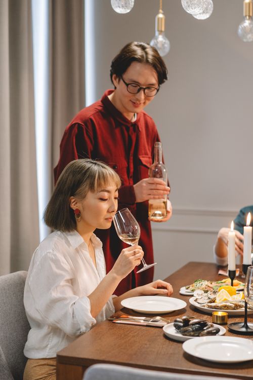 Free A refined dinner setting featuring a couple savoring wine by candlelight, creating an intimate atmosphere. Stock Photo