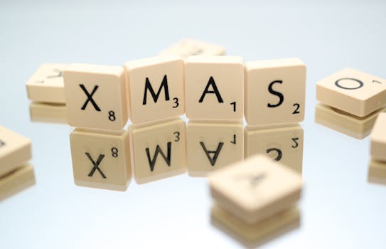 Scrabble tiles spelling 'XMAS' reflecting on a surface. Perfect for holiday-themed content.