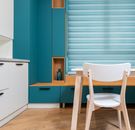 Modern kitchen interior with decorative vase on shelf of cabinet and window blind against table in house
