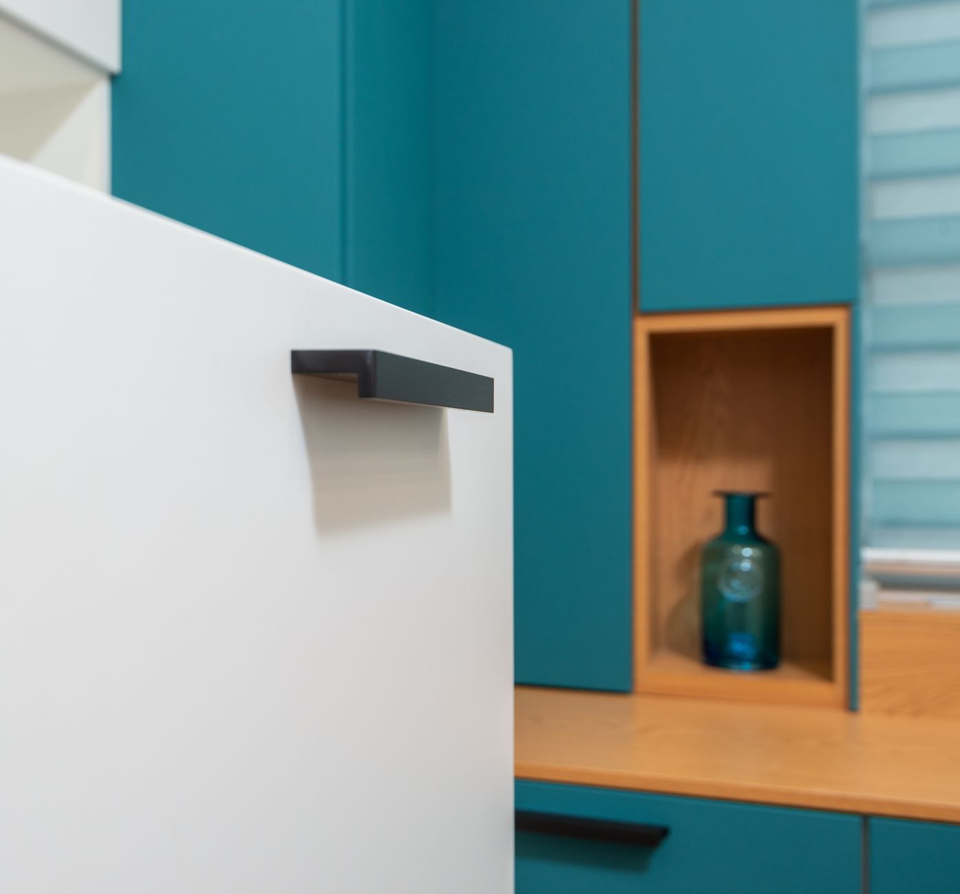 White drawer with plastic handle and shade against decorative vase on shelf of cabinet in light house