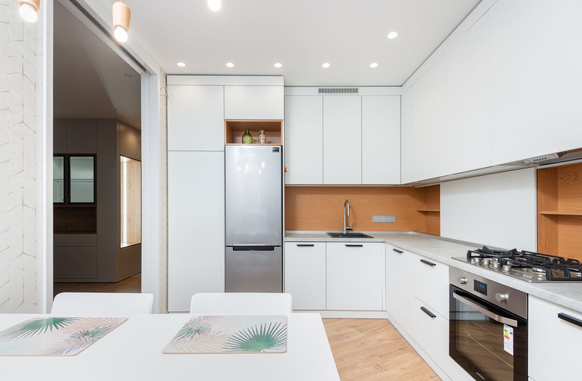 Contemporary white kitchen with glossy cabinets and modern lighting