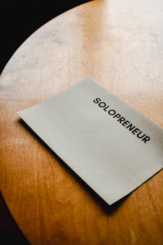 Close-up of a solopreneur concept displayed on paper over a wooden table.
