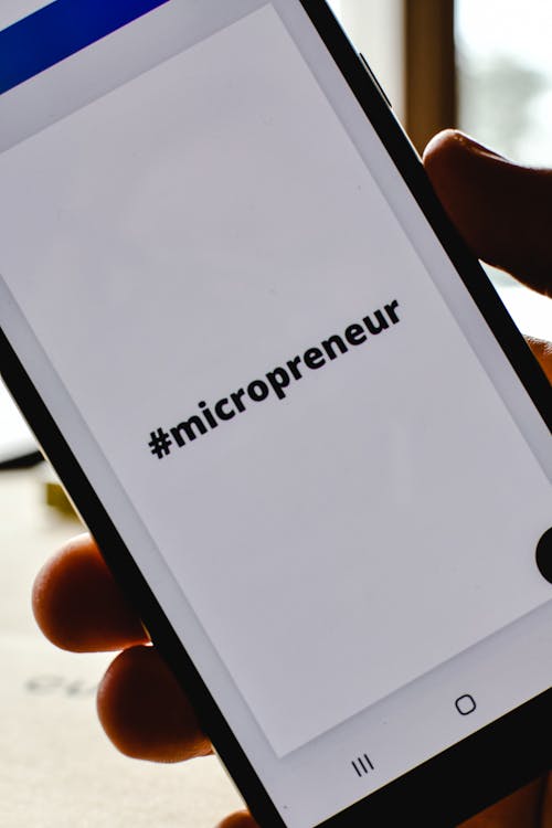 Close-Up Shot of a Person Holding a Mobile Phone with a Micropreneur Text on the Screen