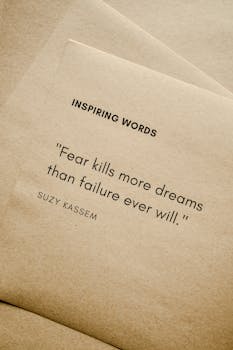 Motivational quote 'Fear kills more dreams than failure ever will.' by Suzy Kassem on paper texture.