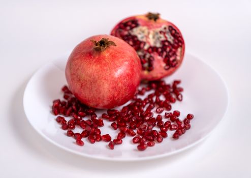 Close-up of fresh and juicy pomegranates on a white plate, highlighting organic red seeds.