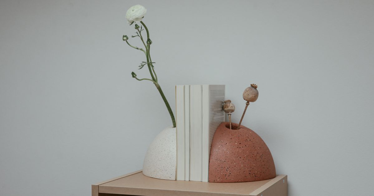 Two curved bookends holding a row of white-spined books on a light wooden shelf