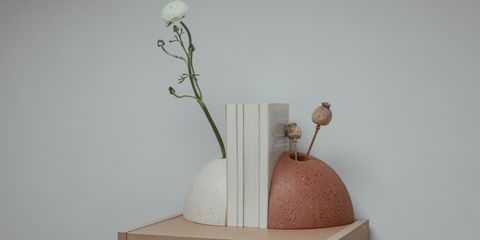 Two curved bookends holding a row of white-spined books on a light wooden shelf