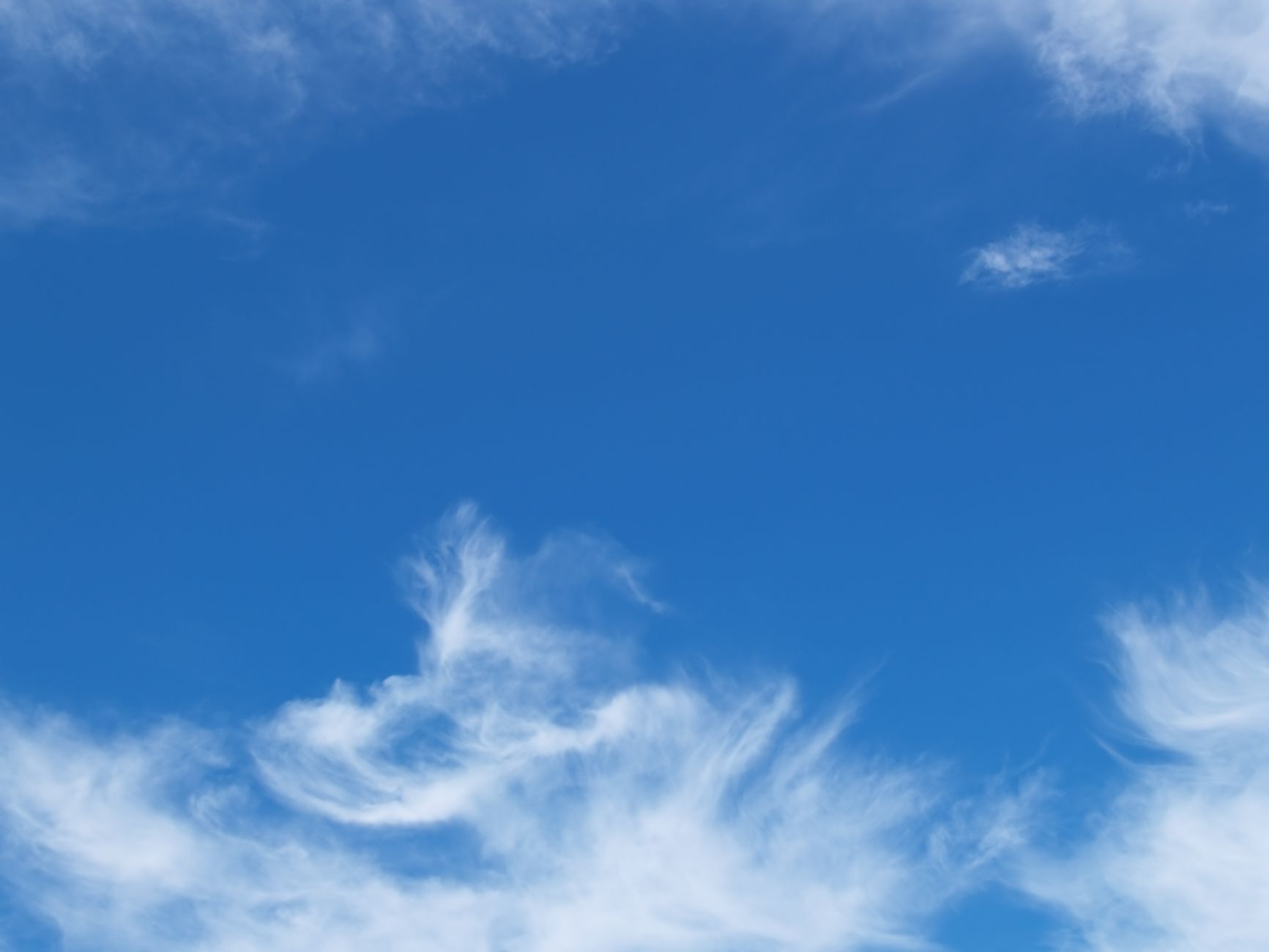 Clear blue sky with soft, fluffy white clouds forming beautiful patterns.