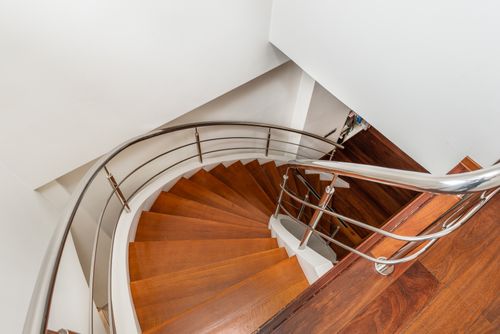 Free From above of wooden curved staircase with metal handrails between white walls at home Stock Photo