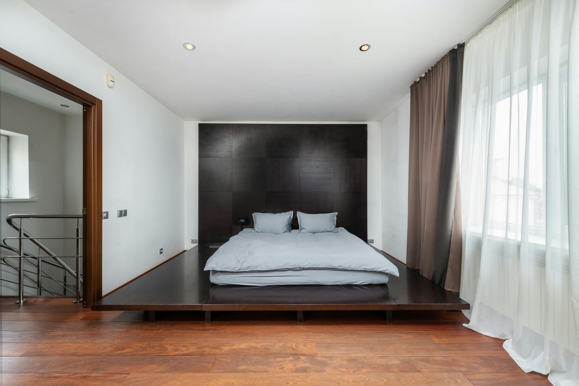 Modern minimalist bedroom with wooden flooring and cozy bed setup.