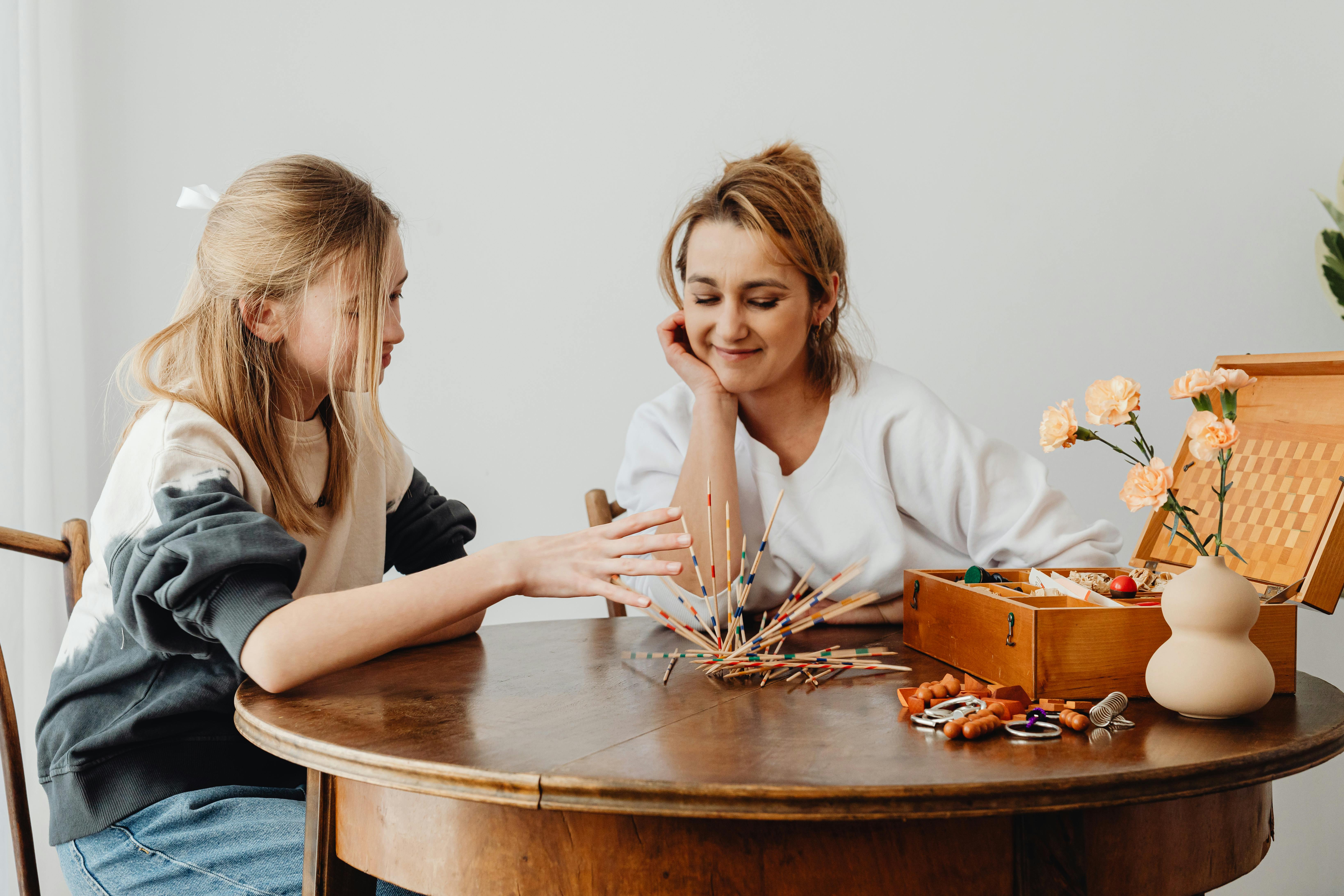 Women Sitting at the Table Playing Sticks Game · Free Stock Photo
