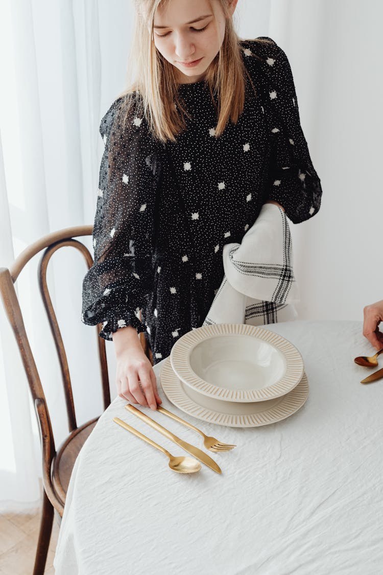 A Young Woman Setting A Dining Table