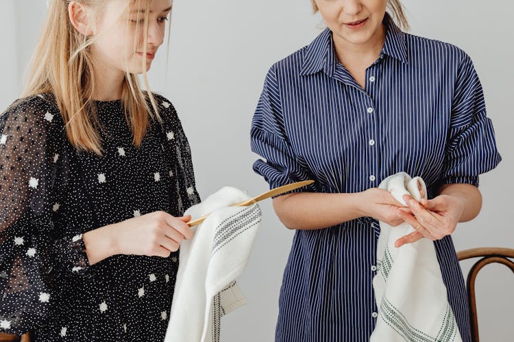 Close Up Of Women In Pattern Dresses Drying Cutlery With Tea Towels