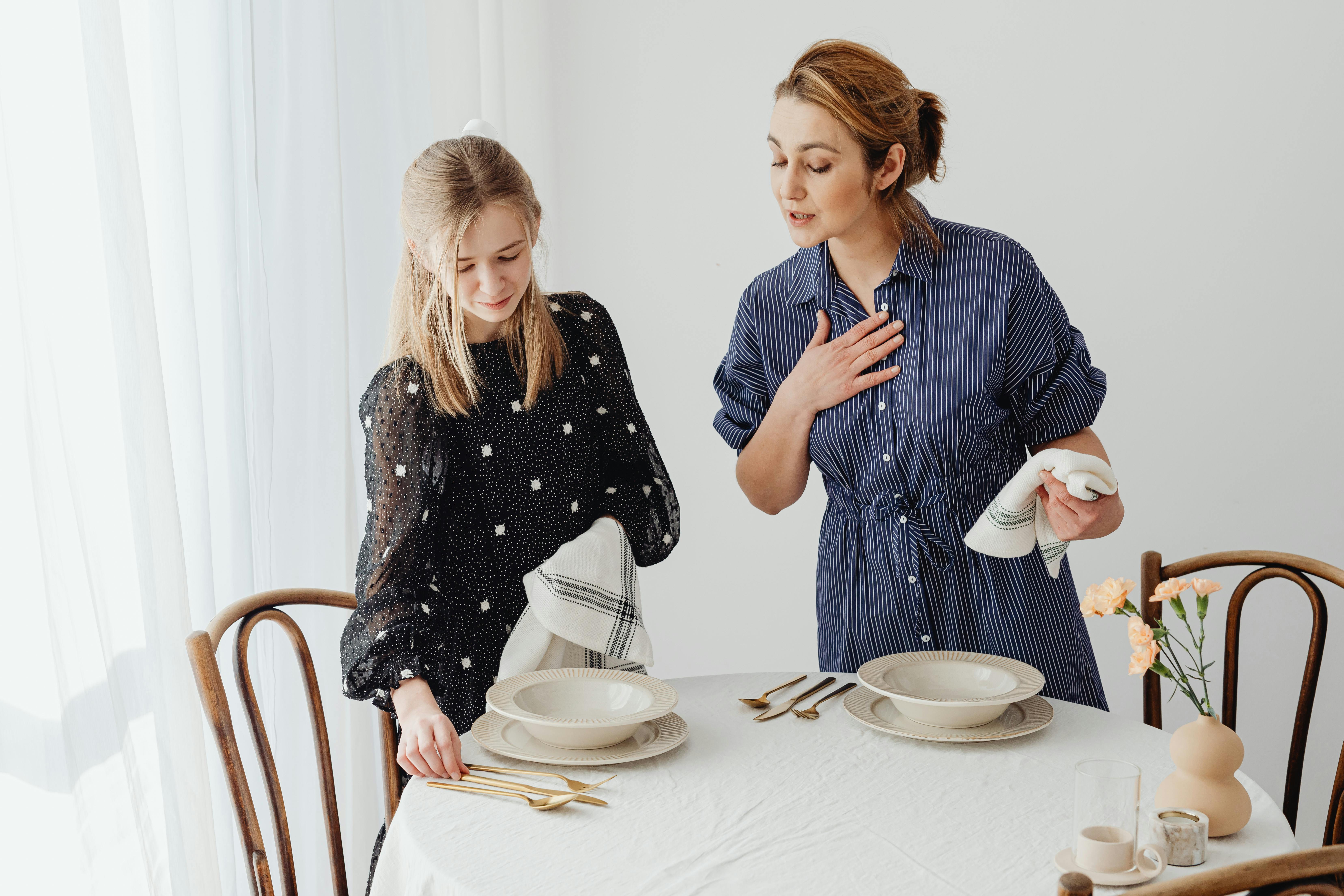 a young woman learning how to arrange utensils in a dining table