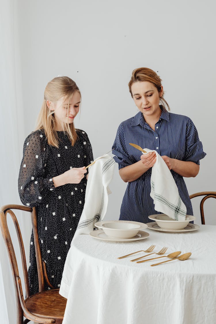 Mother And Daughter Serving Table At Home