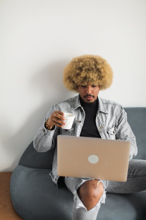 Free Man Holding A Plastic Cup While Using Laptop Stock Photo