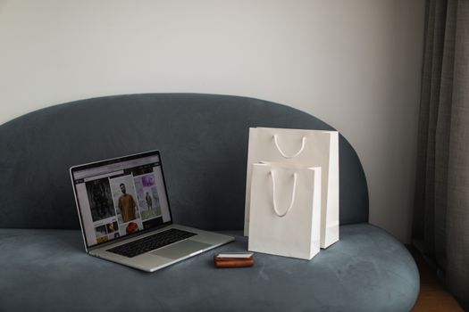 Online shopping setup with a laptop and shopping bags on a stylish couch.