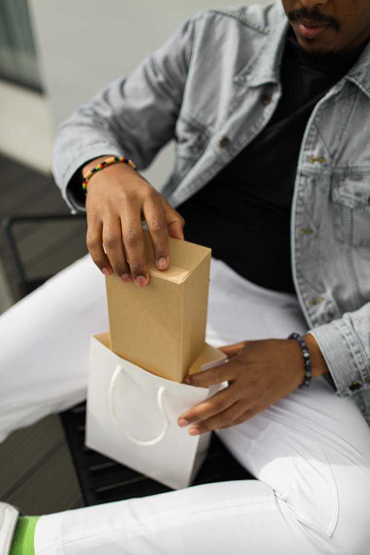 A Person Taking A Box Out Of The Shopping Bag