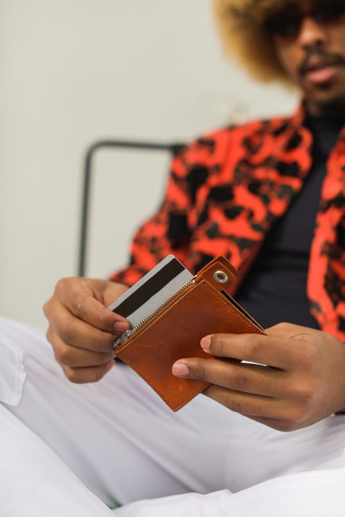 Free Close-up of a fashionable man handling a wallet and credit card in a relaxed setting. Stock Photo