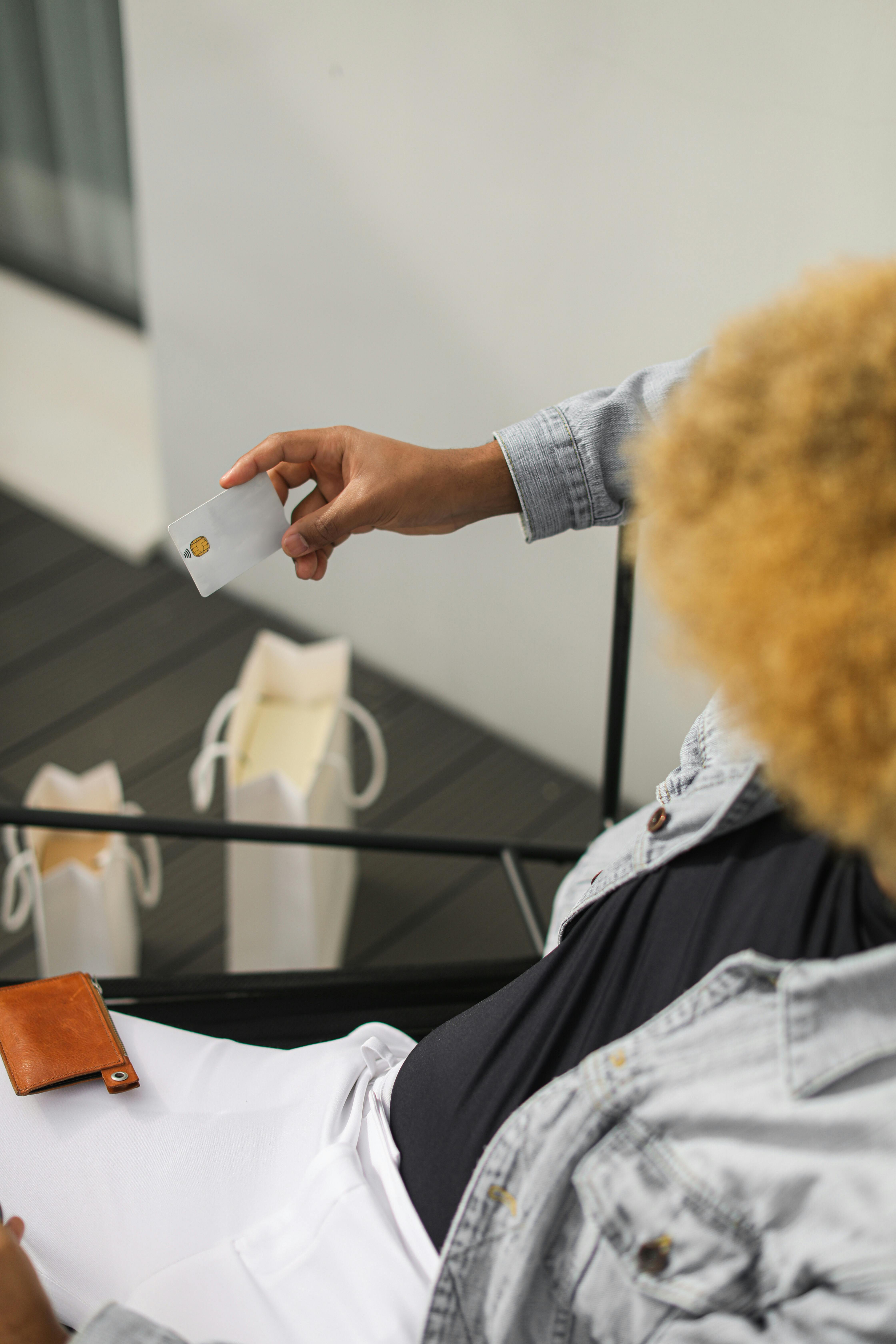 High-angle view of a person holding a credit card with shopping bags on the side, ideal for finance or shopping themes.