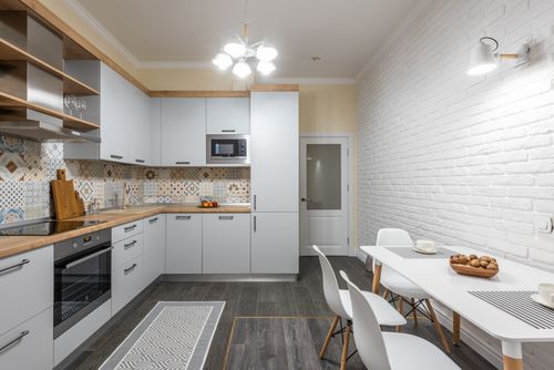 Free Loft style kitchen interior with cabinets and electric appliances against table with cookies and cups under lamp Stock Photo