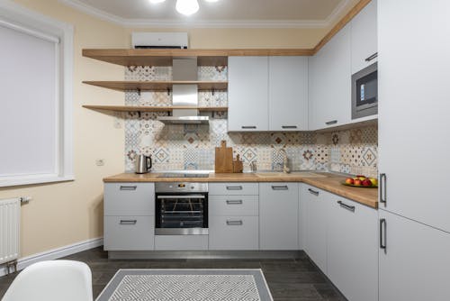 Free Modern kitchen with cabinets and electric stove with oven under hood illuminated by shiny lamp in house Stock Photo