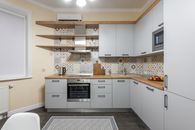Modern kitchen with cabinets and electric stove with oven under hood illuminated by shiny lamp in house
