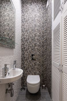 Stylish and compact bathroom featuring modern fixtures, elegant tiles, and a minimalist sink and toilet setup.
