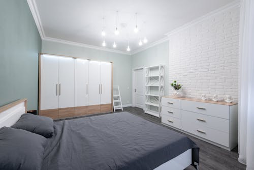 Interior of modern bedroom with minimalist white furniture and comfy bed in apartment