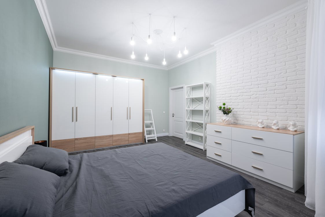 Interior of modern bedroom with minimalist white furniture and comfy bed in apartment