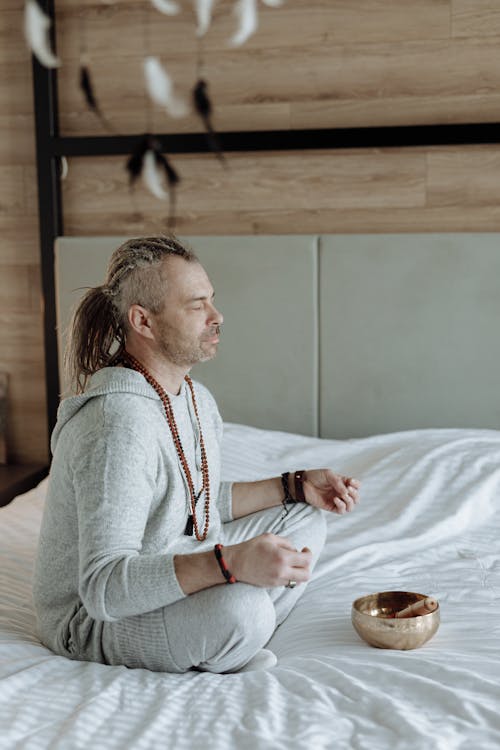 Free Man Meditating on Bed  Stock Photo
