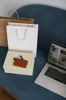 Laptop and shopping bags on a sofa, highlighting modern online shopping.