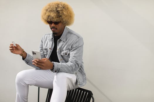Stylish man with afro hairstyle using smartphone and credit card for online shopping.