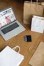 A Laptop and Shopping Bags on the Wooden Floor