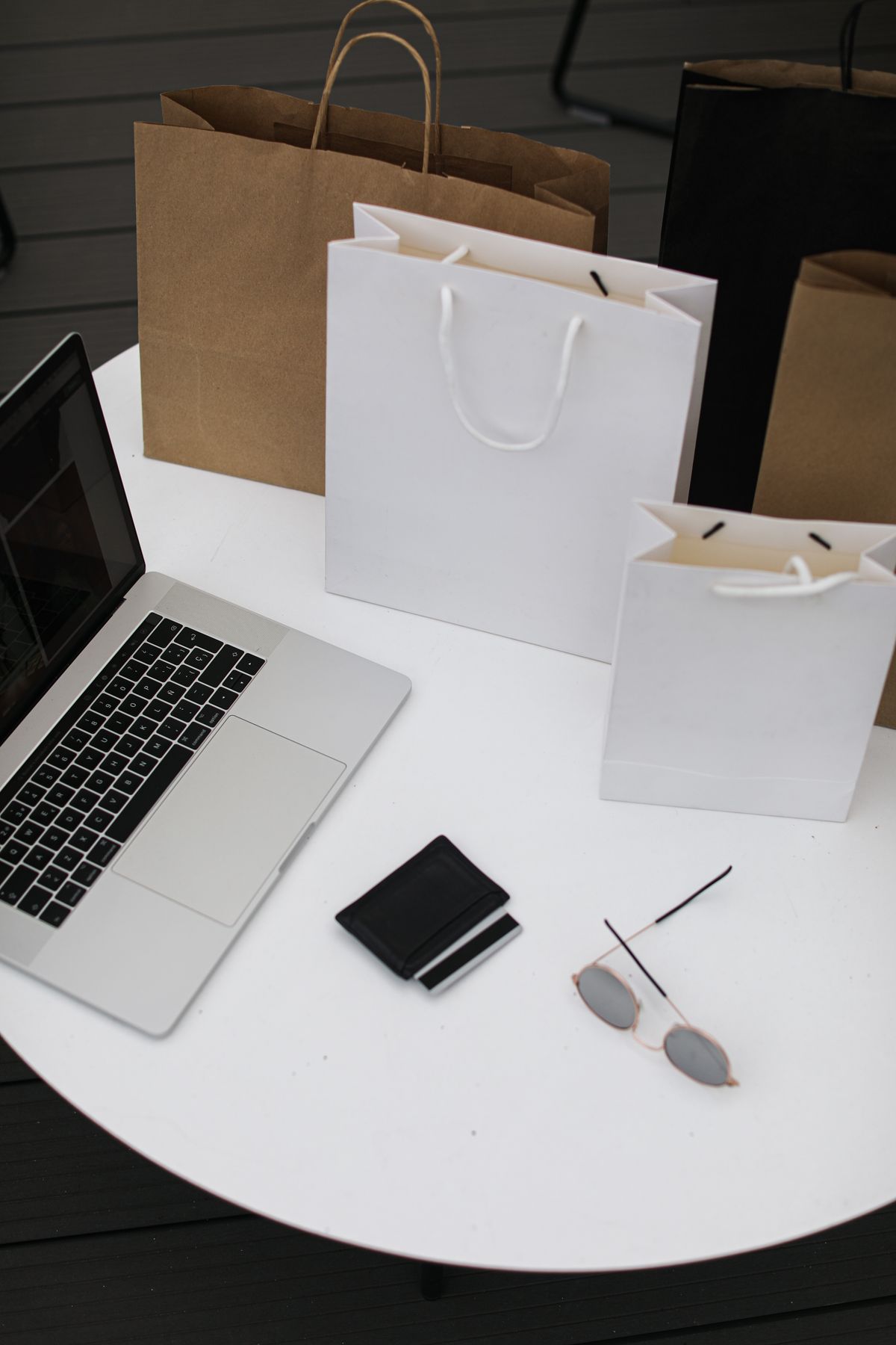 Laptop beside neutral shopping bags on a table