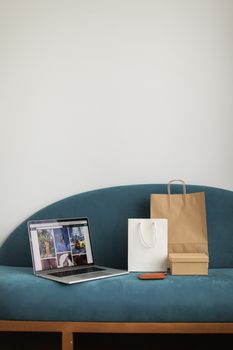 Shopping bags and laptop on sofa, perfect home e-commerce concept for online shopping enthusiasts.