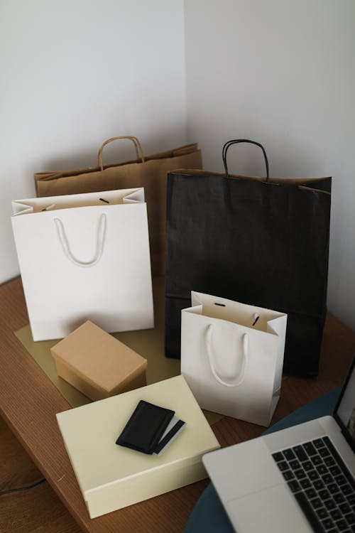Free Shopping Bags From Online Shopping on Brown Wooden Table With Laptop Stock Photo