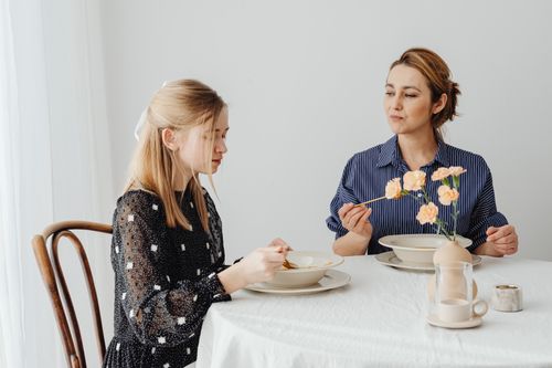 Free A mother and daughter enjoy a peaceful meal together at a dining table adorned with flowers. Stock Photo