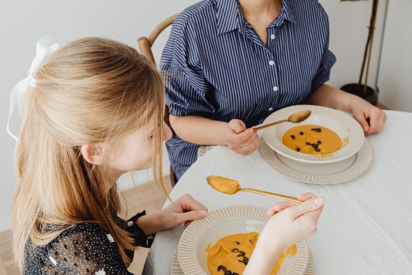 Une maman et sa fille partagent un bol de soupe de potiron dans une ambiance chaleureuse d'automne