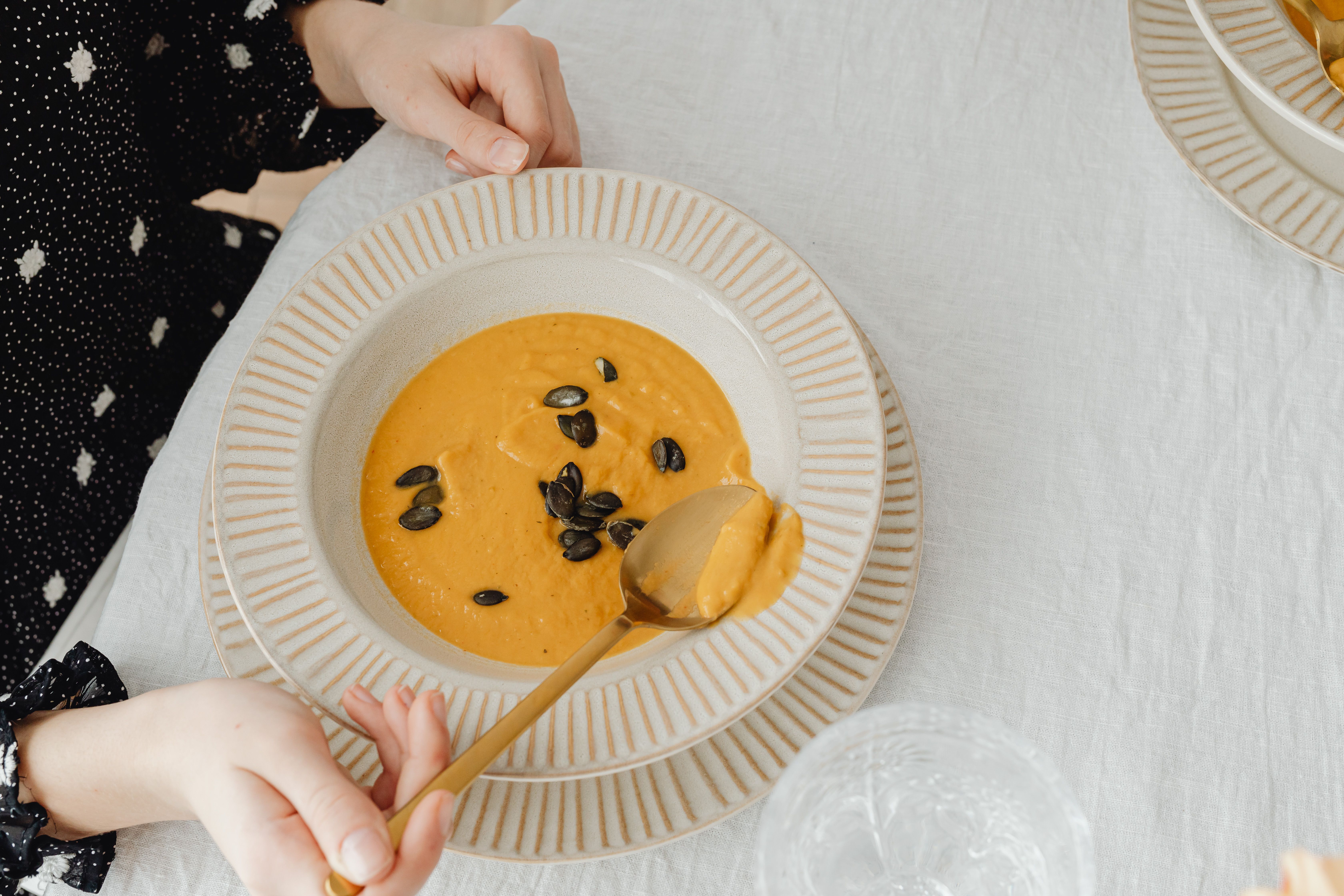 Pumpkin soup with seeds in a ceramic bowl, perfect for a cozy meal.