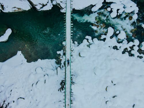 Free An Aerial Photography of a Person Lying on a Snow Covered Bridge Stock Photo