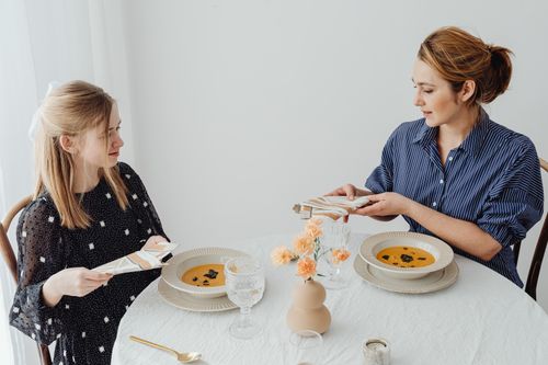 Free Two women dining with soup at an elegantly set table. Stock Photo