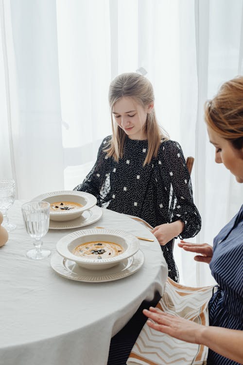Free Women Looking Down at the Table Napkin on their Lap Stock Photo
