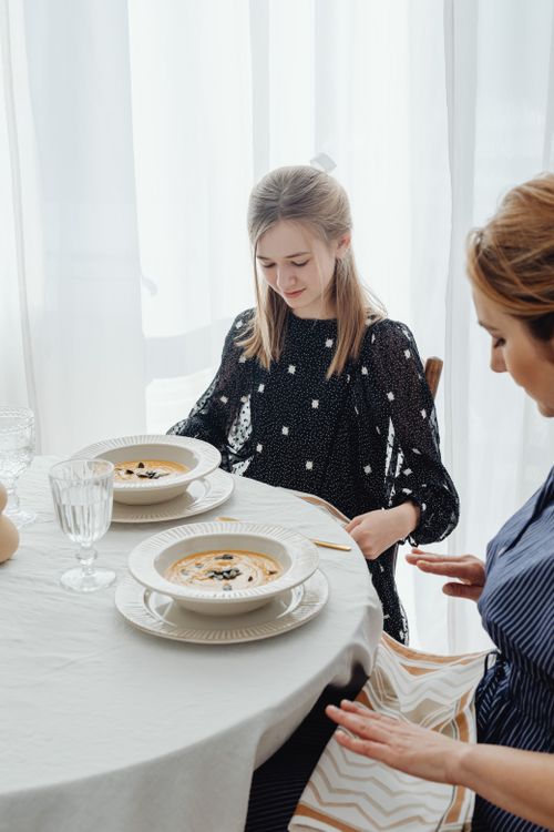 Free Two women sitting and enjoying soup in an elegant indoor dining setting. Stock Photo
