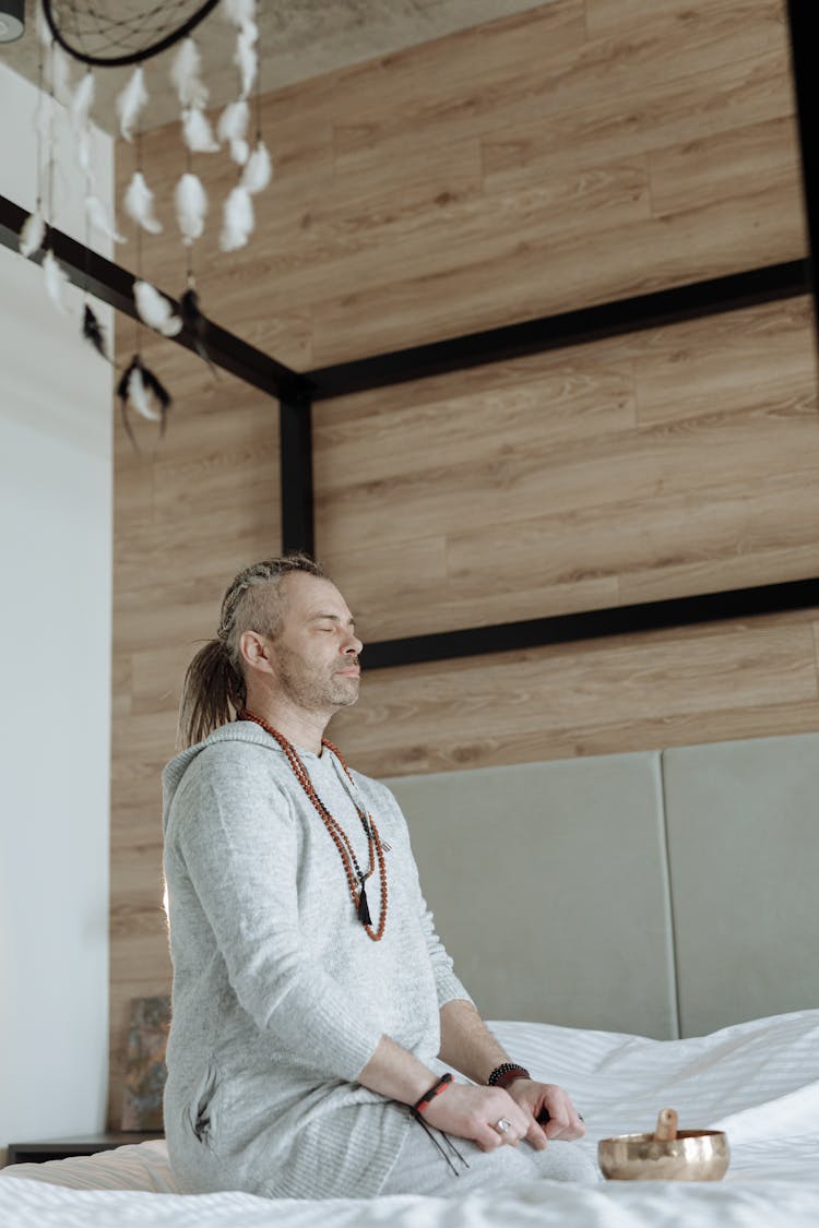 Man Meditating On Bed