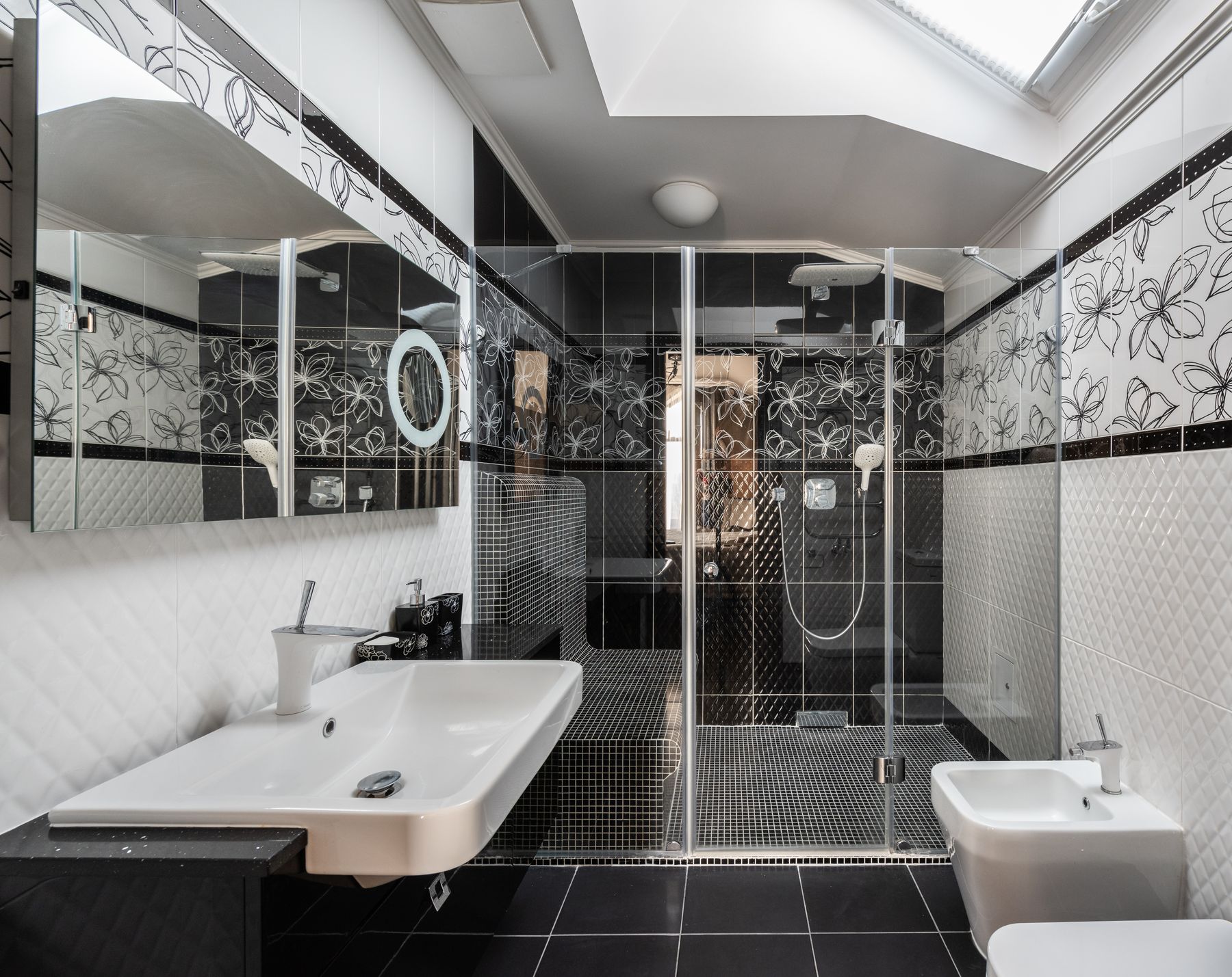 Contemporary black and white bathroom with glass shower, white sink and black floor
