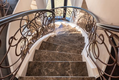 Free From above of spiral stairway with marble steps and metal railings with decorative elements located in modern light building with window Stock Photo